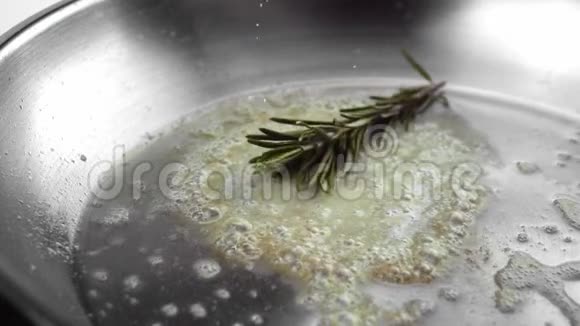 迷迭香和大蒜落在融化的黄油在一个热金属煎锅视频的预览图