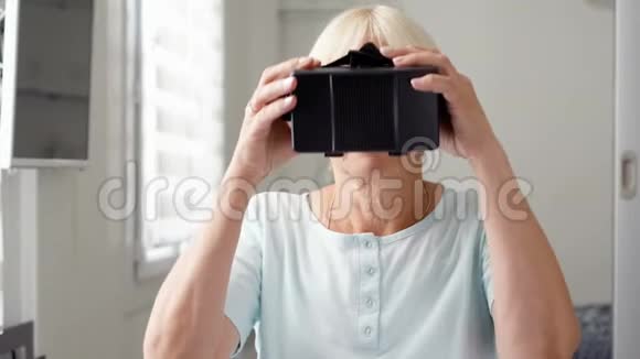 金发资深白女士在家使用VR360眼镜进行浏览缩放和点击手势视频的预览图