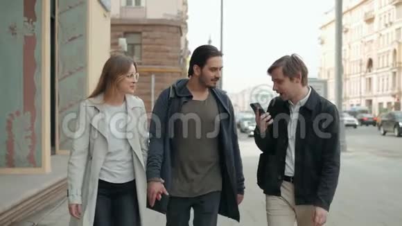 三个惊讶的学生在街上用智能手机查看在线内容快乐的朋友在街上散步视频的预览图