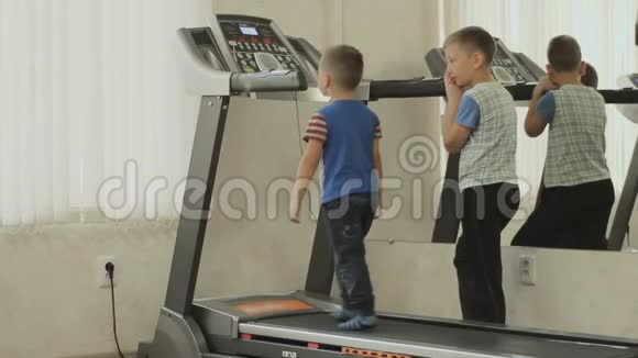 大一点的孩子正在训练小一点的人在跑步机上行走视频的预览图