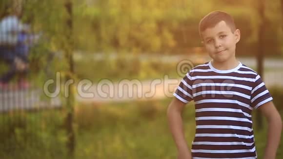 一个穿着条纹T恤的小男孩正在操场上玩在秋千上荡秋千春天视频的预览图