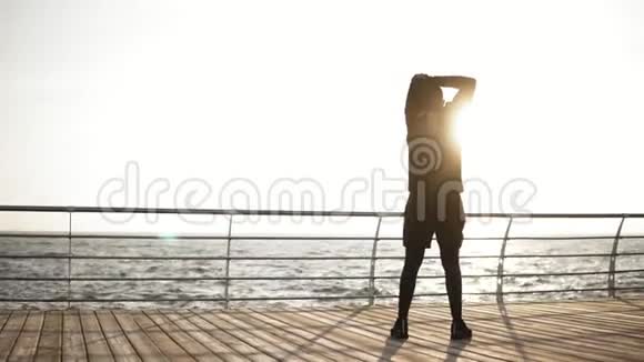 年轻的运动男子在海边的码头上伸展在海岸上阳光明媚的早晨户外录像视频的预览图