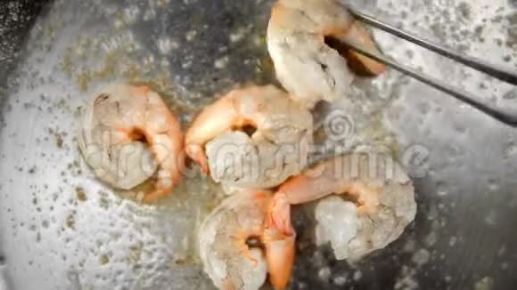 用大蒜和迷迭香在煎锅上的虾苗上厨师把虾转向另一边视频的预览图