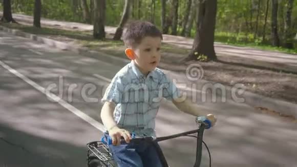 在柏油路骑自行车的小男孩可爱的男孩在自行车道上学骑自行车视频的预览图