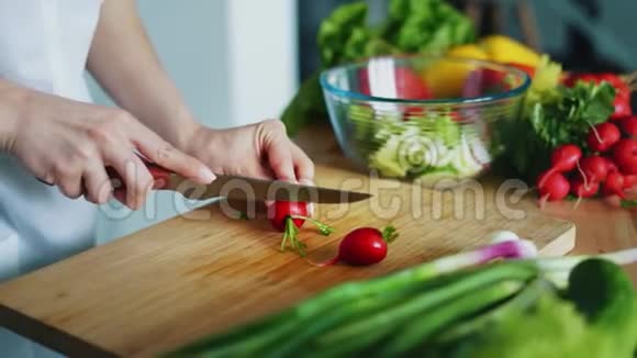 女人的手用刀切萝卜做沙拉把新鲜蔬菜收起来视频的预览图