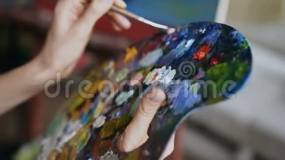 在艺术中用画笔将女性手中的颜料与颜料混合在一起视频的预览图