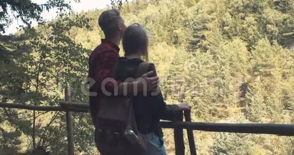 拥抱情侣站在森林里的山上的后景视频的预览图