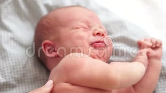 一个两周大的婴儿躺在床上哭妈妈把一个哭泣的孩子抱在怀里新生儿儿童日视频的预览图