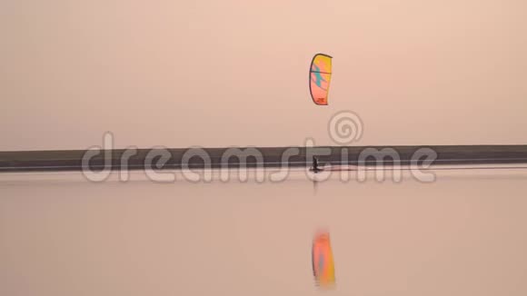 橙色训练风筝一个人在日落时在湖上冲浪慢动作视频的预览图