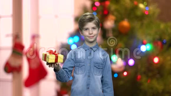 在模糊的圣诞背景上带礼物盒的小男孩视频的预览图