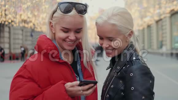 两个有趣的朋友在日落时分在街上自拍背景是温暖的光线女孩们和姐妹在一起视频的预览图