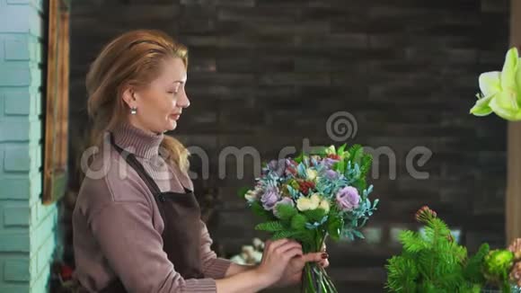 一个穿着围裙的女花匠站在一家花店的柜台上准备一束花视频的预览图