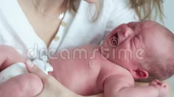 一个两周大的婴儿在他母亲的怀里哭新生儿的绞痛母亲安抚她哭泣的婴儿视频的预览图
