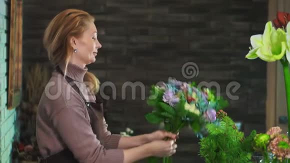 一个穿着围裙的女花匠站在一家花店的柜台上准备一束花视频的预览图