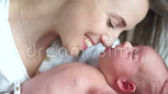 一个新生婴儿在母亲的怀里打哈欠妈妈在对她的孩子微笑母亲节视频的预览图