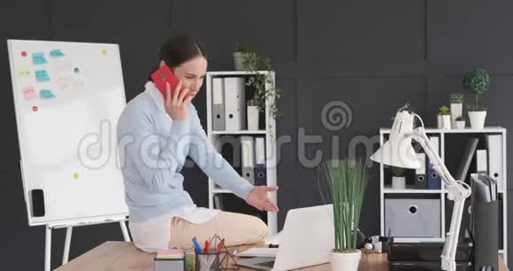 女商人在办公室用手机和笔记本电脑说话视频的预览图