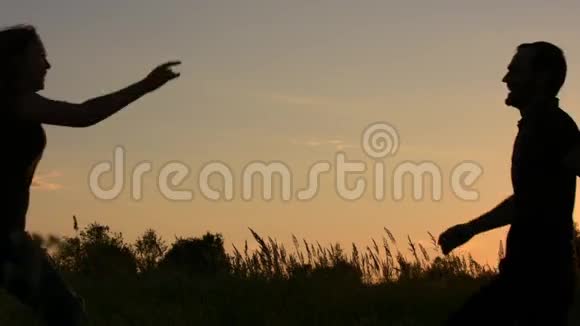快乐的年轻女子扑向他的朋友在夕阳的天空背景上视频的预览图
