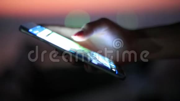 人类手在日落海滩海边使用移动智能手机有模糊的bokeh灯1920x1080视频的预览图