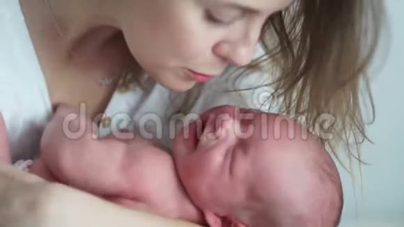 一个新生婴儿在他母亲的怀里哭新生儿的绞痛母亲安抚她哭泣的婴儿新生儿健康视频的预览图