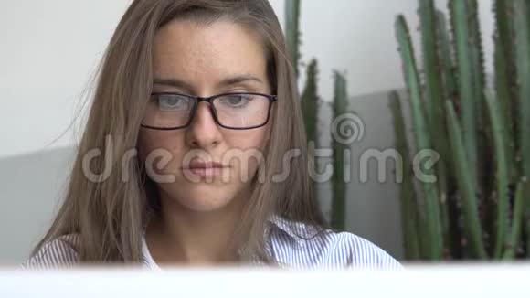 戴眼镜的女记者在笔记本电脑上打字视频的预览图