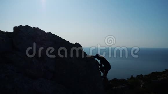 年轻的长发男子举起双手站在海面上一座山的顶端与美丽的山对着视频的预览图