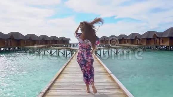 马尔代夫海滩上有透明海水的妇女在桥上奔跑视频的预览图