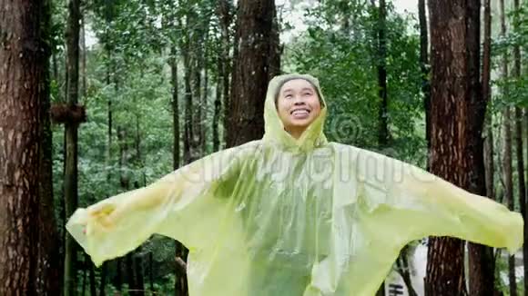 穿黄色雨衣的亚洲女人站在雨中视频的预览图
