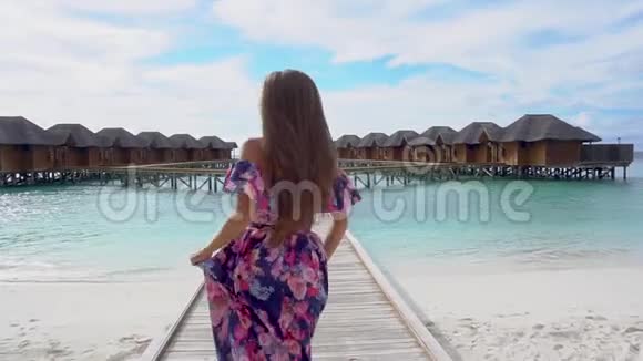 马尔代夫海滩上有透明海水的妇女在桥上奔跑视频的预览图