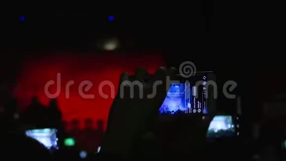 现代科技手里拿着电话的崇拜者在舞台上欣赏摇滚表演视频的预览图