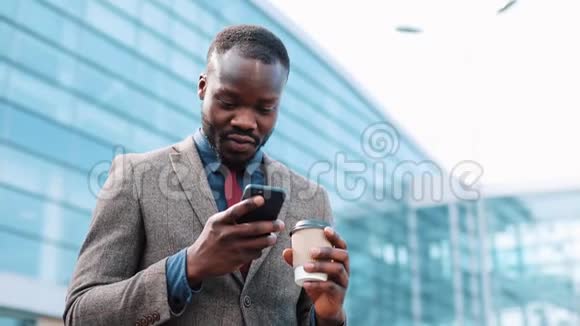 快乐的非裔美国人成功的商人在智能手机上得到了好消息他站在一个办公中心附近智能手机视频的预览图
