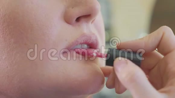 年轻的化妆师在模特的嘴唇上涂口红视频的预览图