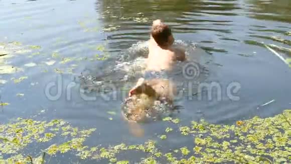 夏天十几岁的男孩正在一条野河里洗澡自然条件下河上的浮萍视频的预览图