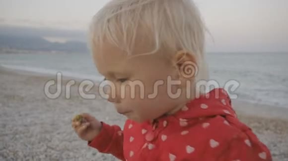 特写两岁宝宝吃青橄榄并微笑的海边背景视频的预览图