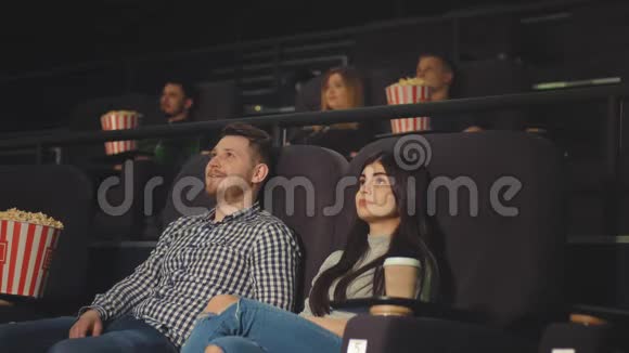 一个年轻人和一个朋友在电影院看电影并且嘲笑他们在屏幕上看到的东西视频的预览图