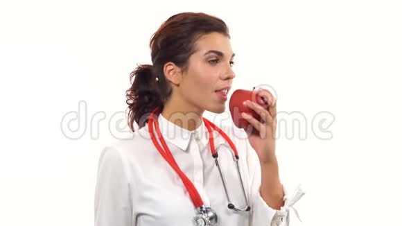 年轻友好的女营养学家展示一个红苹果咬它微笑建议健康饮食青年肖像视频的预览图