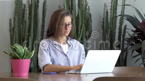 戴眼镜的女记者在笔记本电脑上打字视频的预览图
