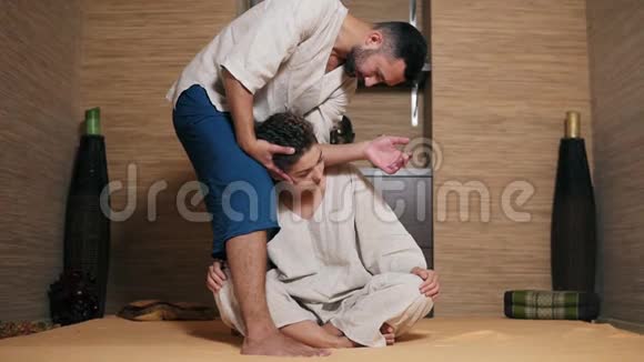 泰国男性按摩师正在按摩年轻女子脖子他的肘部站在她身边一个美丽的女孩视频的预览图