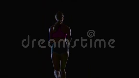运动健身女子在黑色背景下运行后视镜剪影慢动作视频的预览图