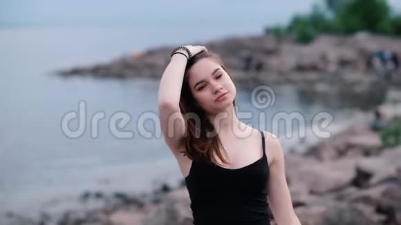 美丽的年轻女孩黑发在海边日落的光慢动作视频的预览图