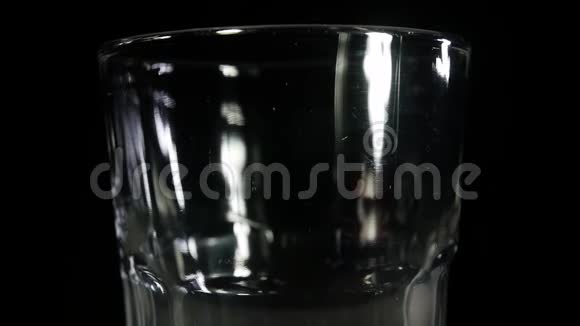 黑啤酒倒在黑背景上的玻璃杯里快关门慢动作视频的预览图