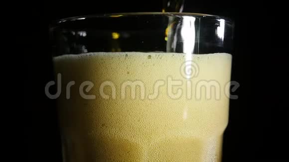 黑啤酒倒在黑色背景上的冷玻璃里快关门慢动作视频的预览图