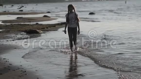 小女孩在沙滩上慢悠悠地走着视频的预览图