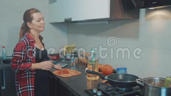 女孩在锅里炒胡萝卜女人在家里的厨房做饭做烤年轻女子加胡萝卜的肖像视频的预览图