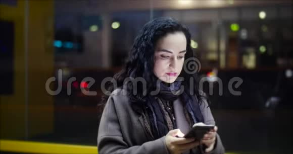 美丽快乐的年轻女人穿着棕色外套带着深蓝色围巾和长长的深色卷发享受咖啡忙着和她在一起视频的预览图