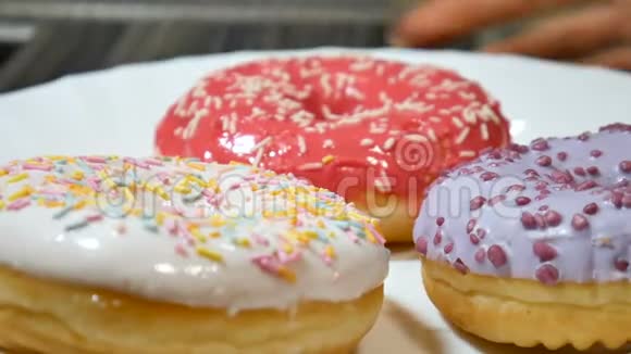 美味的红色白色和紫色甜甜圈白色盘子上撒着五颜六色的花视频的预览图