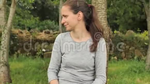 4k灰色女孩微笑着触摸她的手机在绿色田野山丘和棕榈园的农村背景下视频的预览图