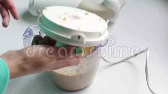 女人用粉碎的蔬菜团打开搅拌机从里面拿出一把刀视频的预览图