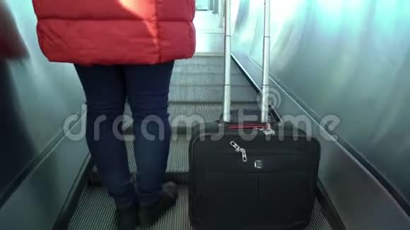 提着手提箱走上自动扶梯的年轻女子视频的预览图