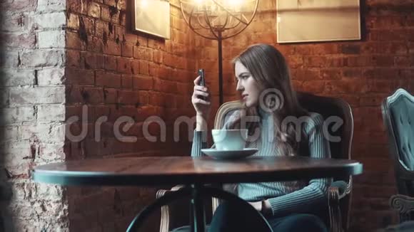咖啡馆里一个漂亮女孩的肖像女孩在相机智能手机和饮料上自拍视频的预览图