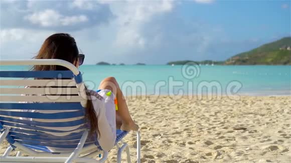 暑假的时候躺在沙滩上晒太阳的女人放松和享受慢动作视频的预览图